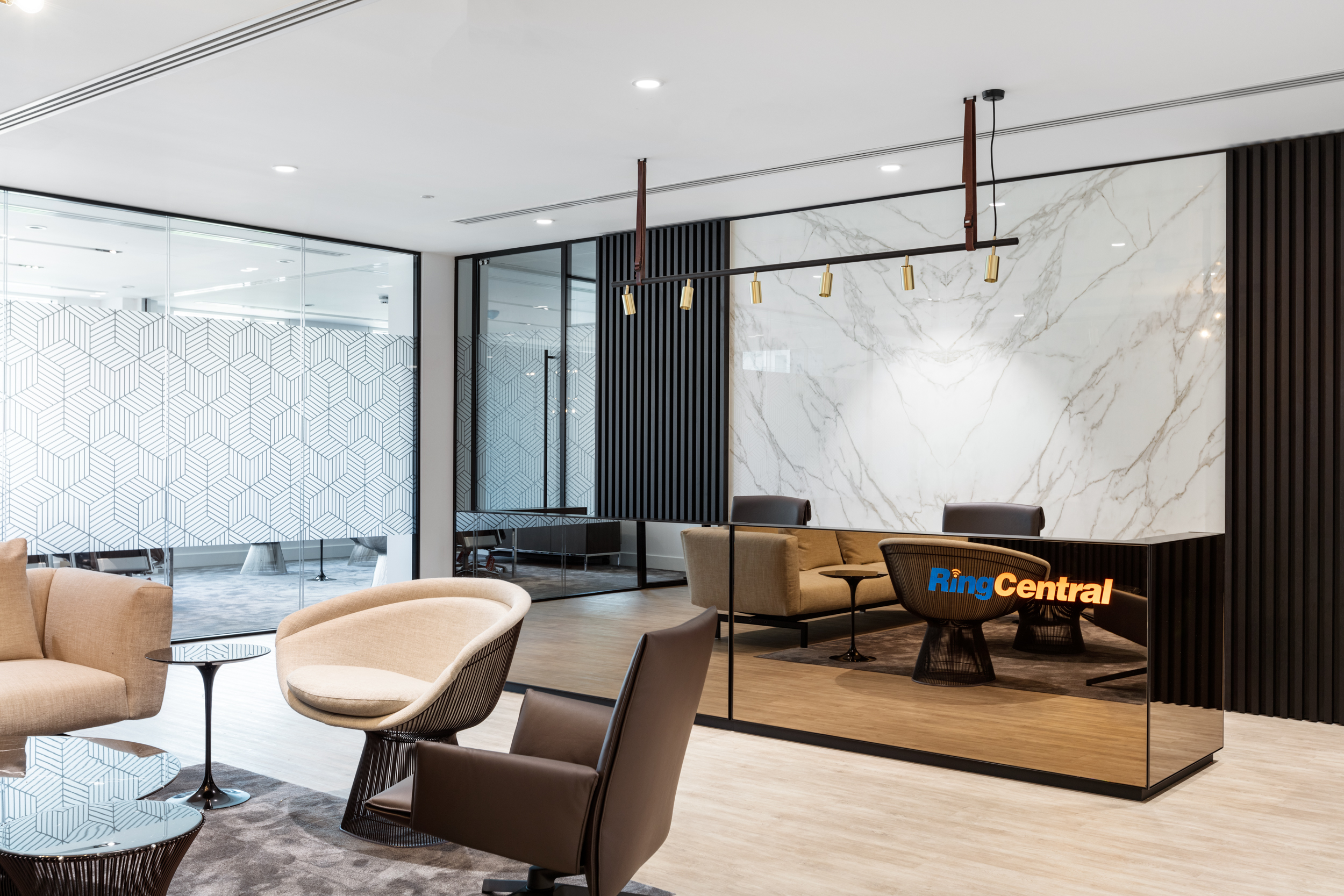 A contemporary reception area at Ring Central featuring a marble wall backdrop, elegant seating, and modern lighting, exuding a sophisticated and welcoming atmosphere.