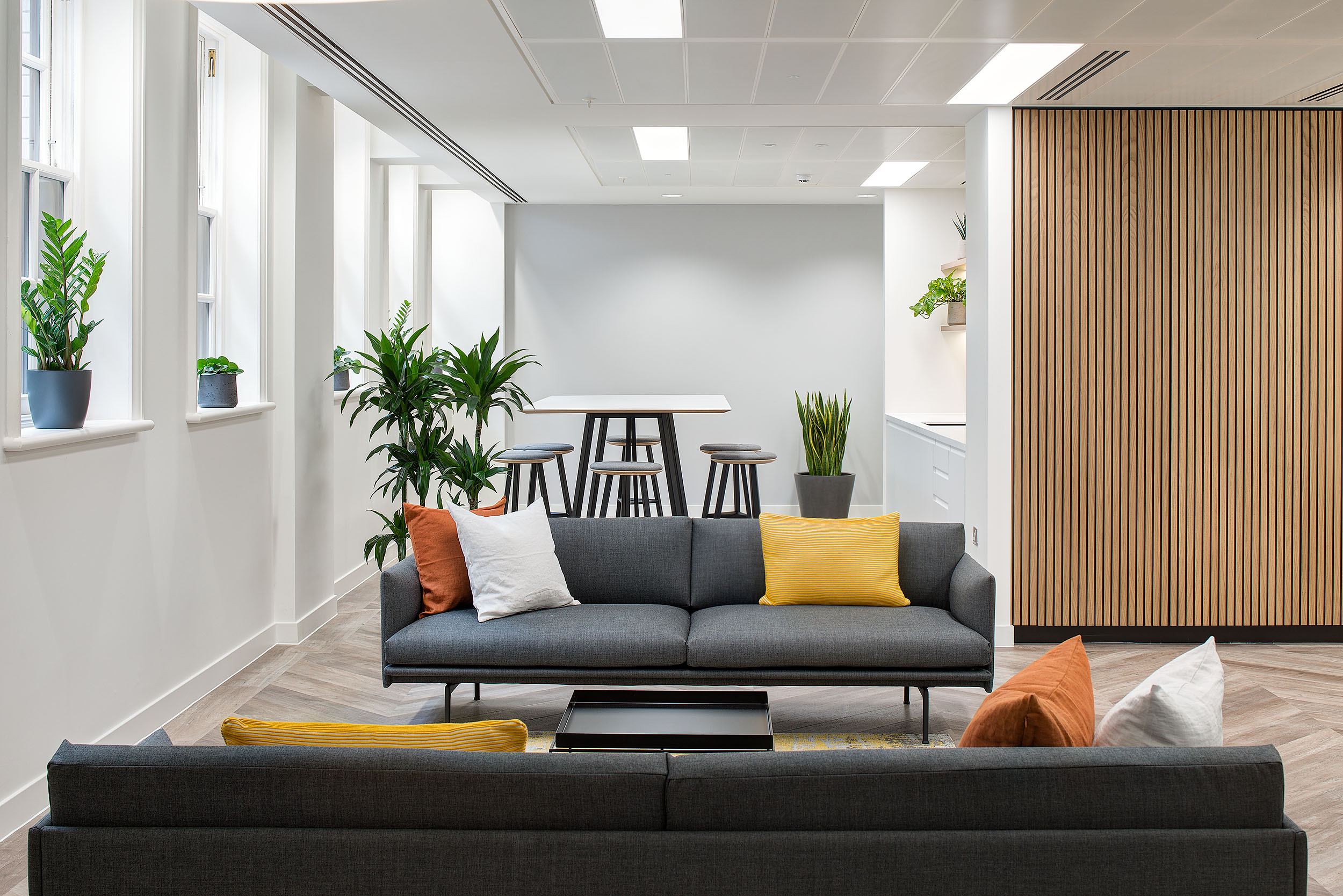 Casual seating area at 20 St James Street Level 1, with sofas, colourful cushions, and plants creating a cosy breakout space.