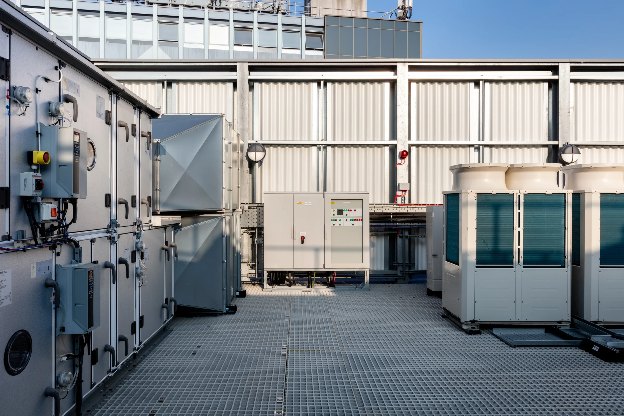 Close-up of rooftop ventilation and control systems at the Programme Building, highlighting the structured arrangement of industrial equipment against a corrugated backdrop.