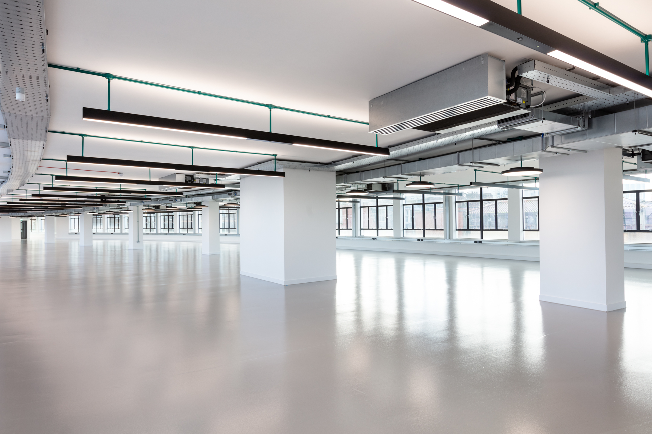 Another view of the open-plan space at Programme Building, with a focus on the clean lines and industrial design elements. The space is illuminated by natural light and modern ceiling fixtures.