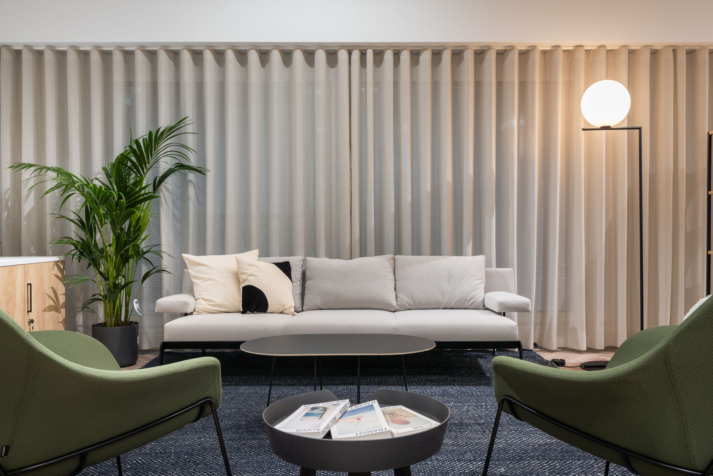 Contemporary seating area with grey sofa and green chairs at One Strand, created by Ambit for tenant flexibility