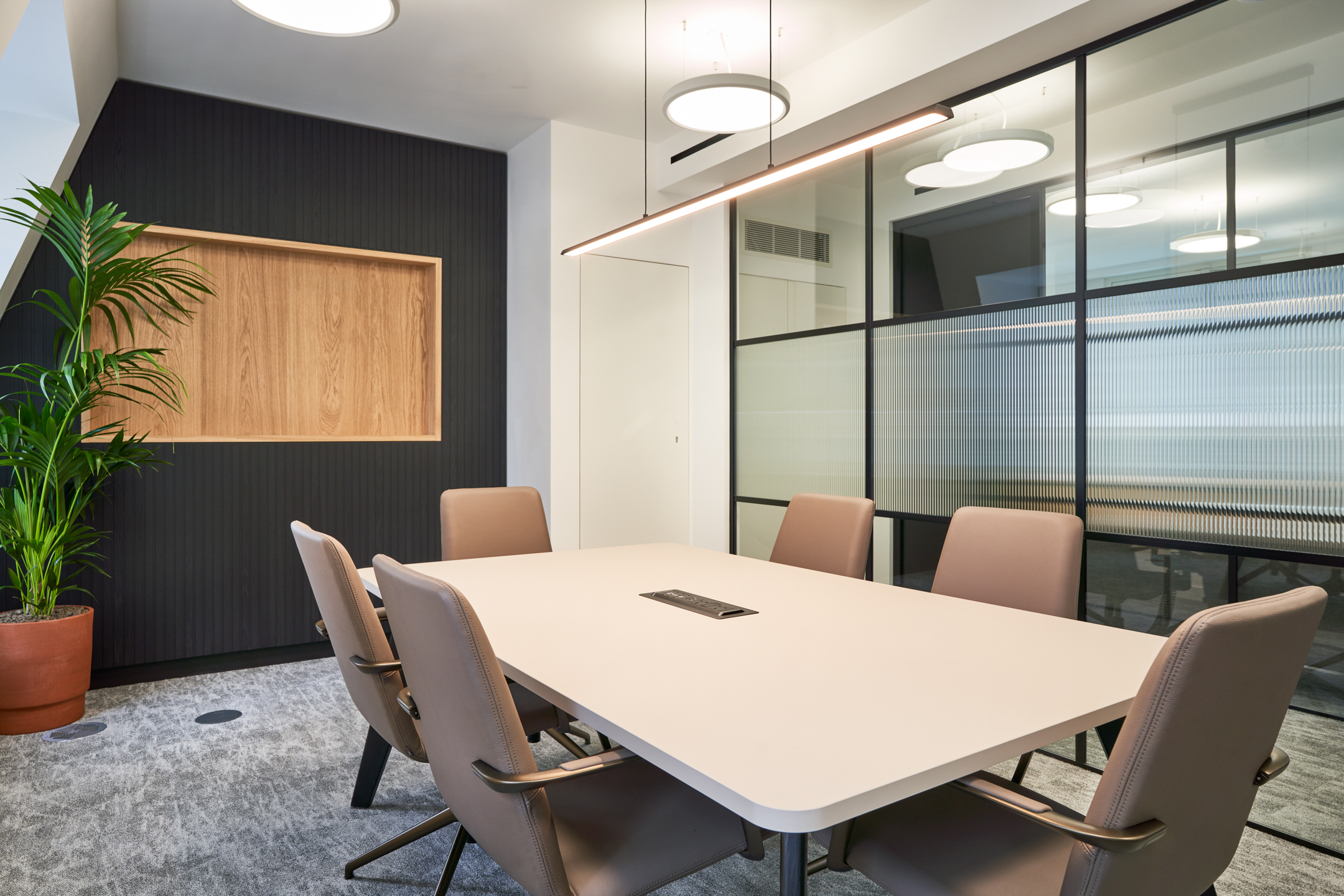 Contemporary meeting room at 3 St Helens Place featuring a large table, comfortable chairs, a potted plant, and frosted glazing for privacy.