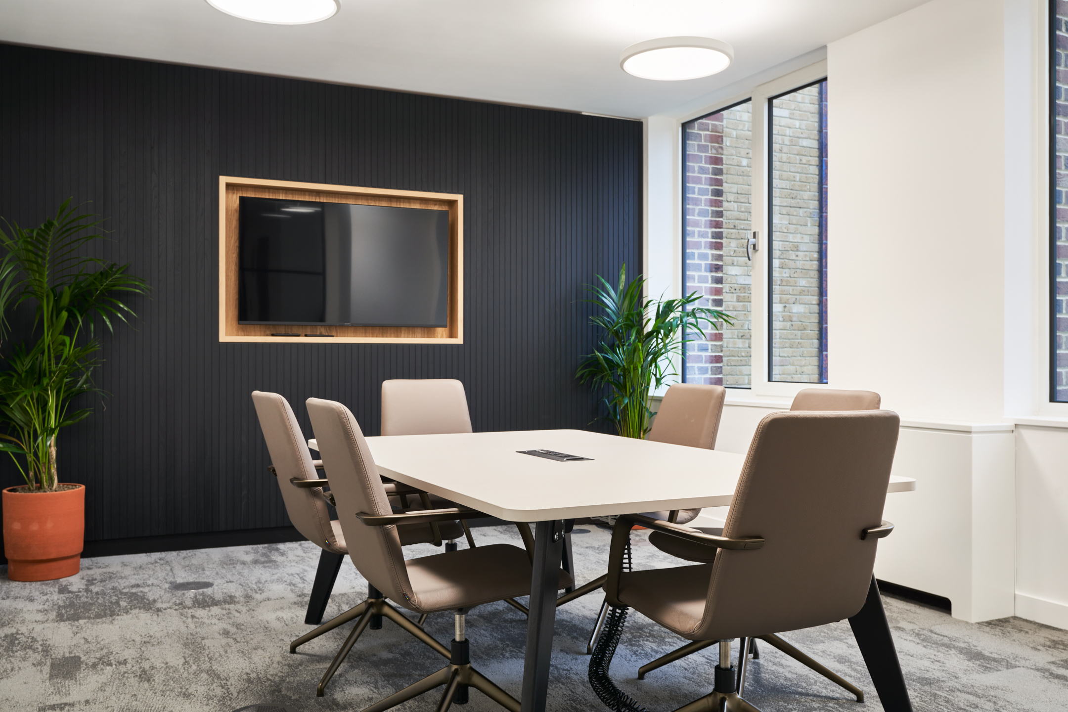 Small meeting room at 3 St Helens Place with a modern table, comfortable chairs, wall-mounted screen, and indoor plants.