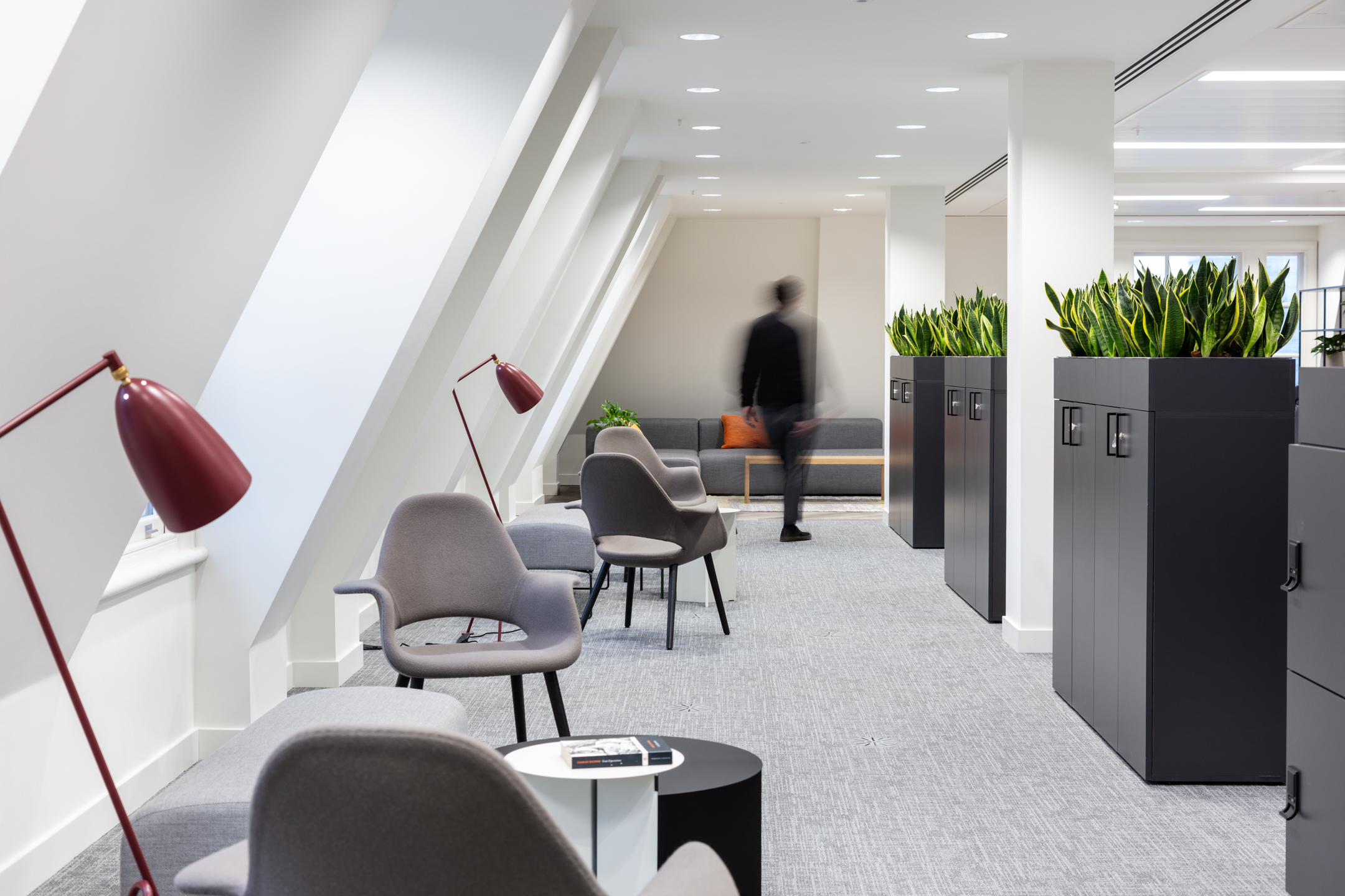 Hallway at 20 St James’s Street, Level 8 with lounge chairs, planters, and integrated lighting, leading to a spacious seating area; blurred motion adds a dynamic touch.