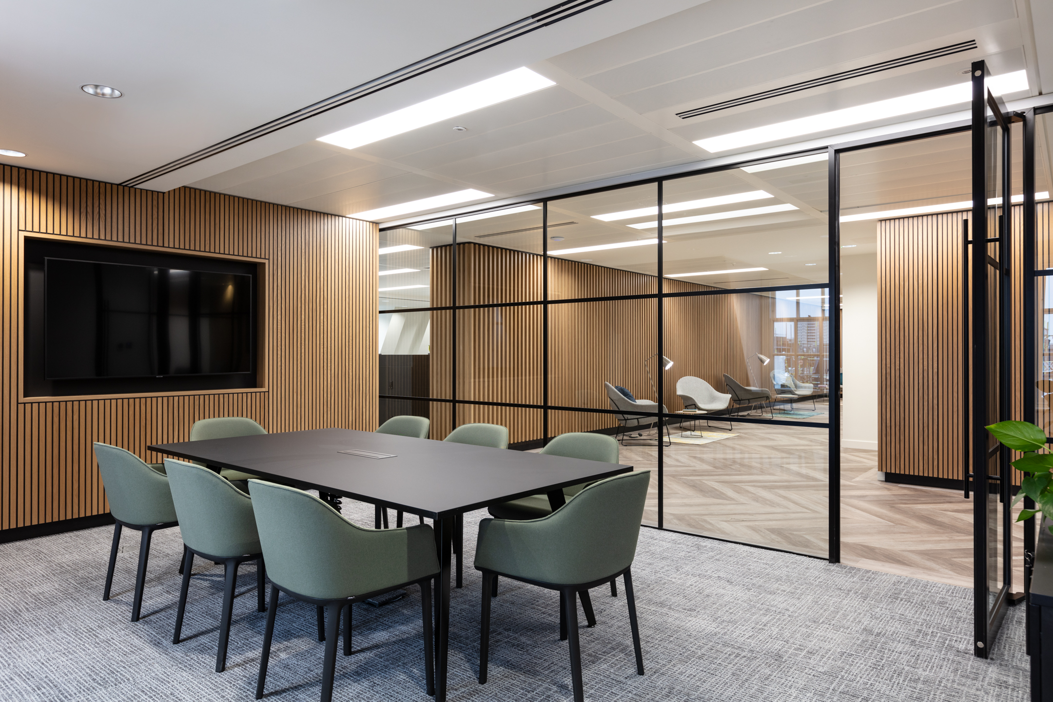 20 St James’s Street, Level 8 meeting room with a minimalist black table, green chairs, and floor-to-ceiling glass partitions, connecting to an adjoining lounge.