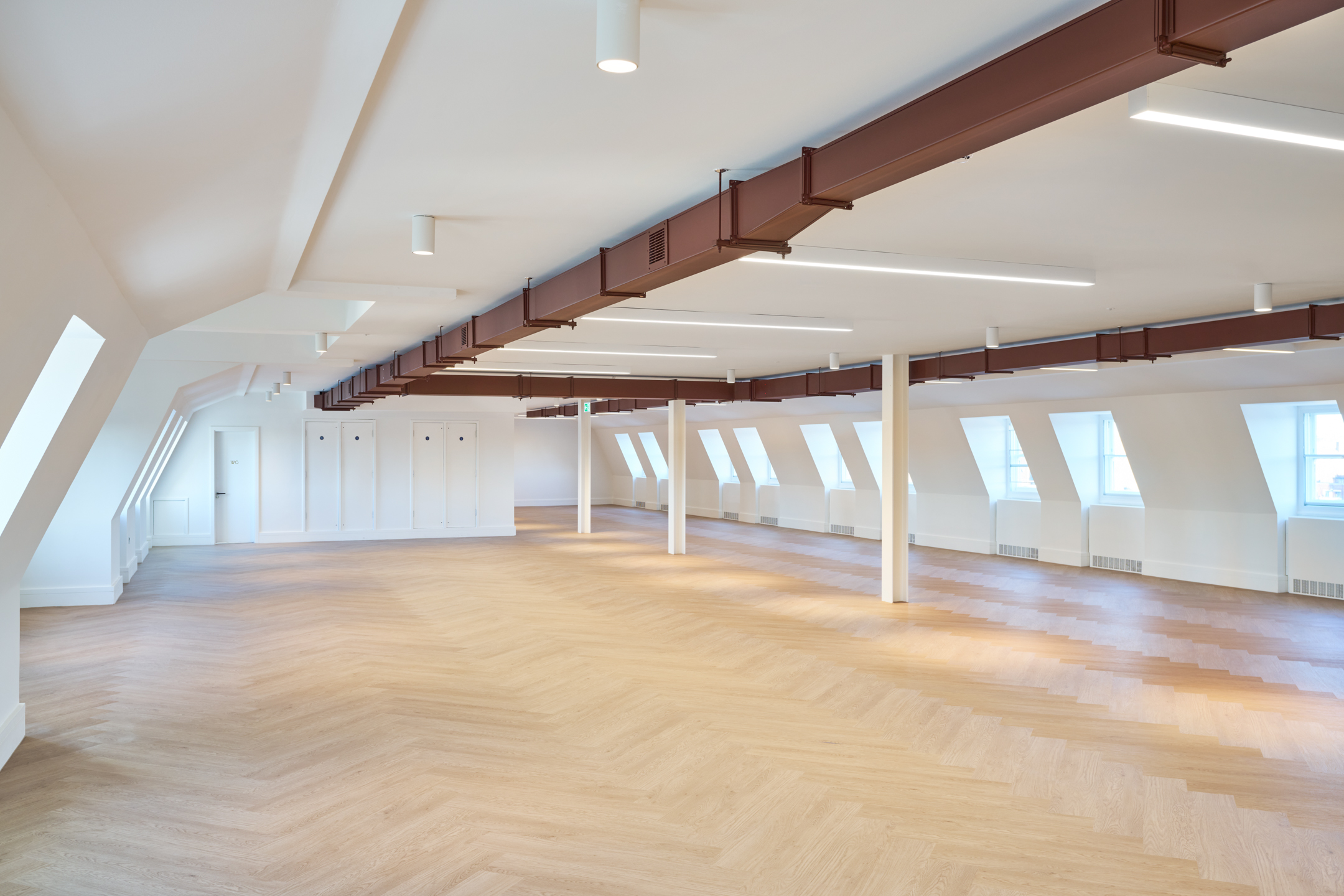 Spacious room at 163-203 Eversholt Street, featuring light wood flooring, ceiling beams, and natural lighting from skylight-style windows.