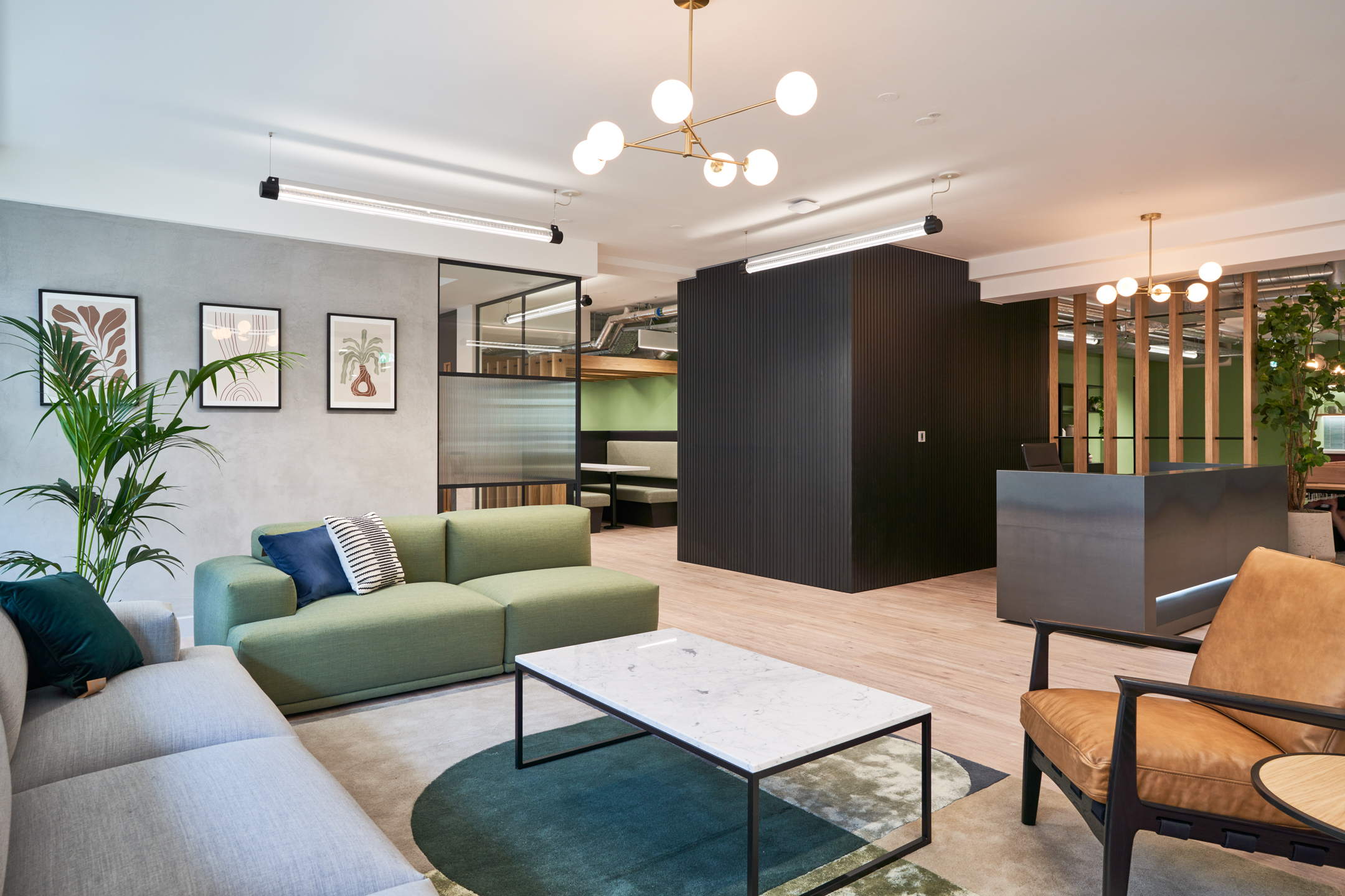 Stylish office lounge at 101 New Cavendish Street, Level 2, featuring green sofas, minimalist décor, and a marble coffee table.