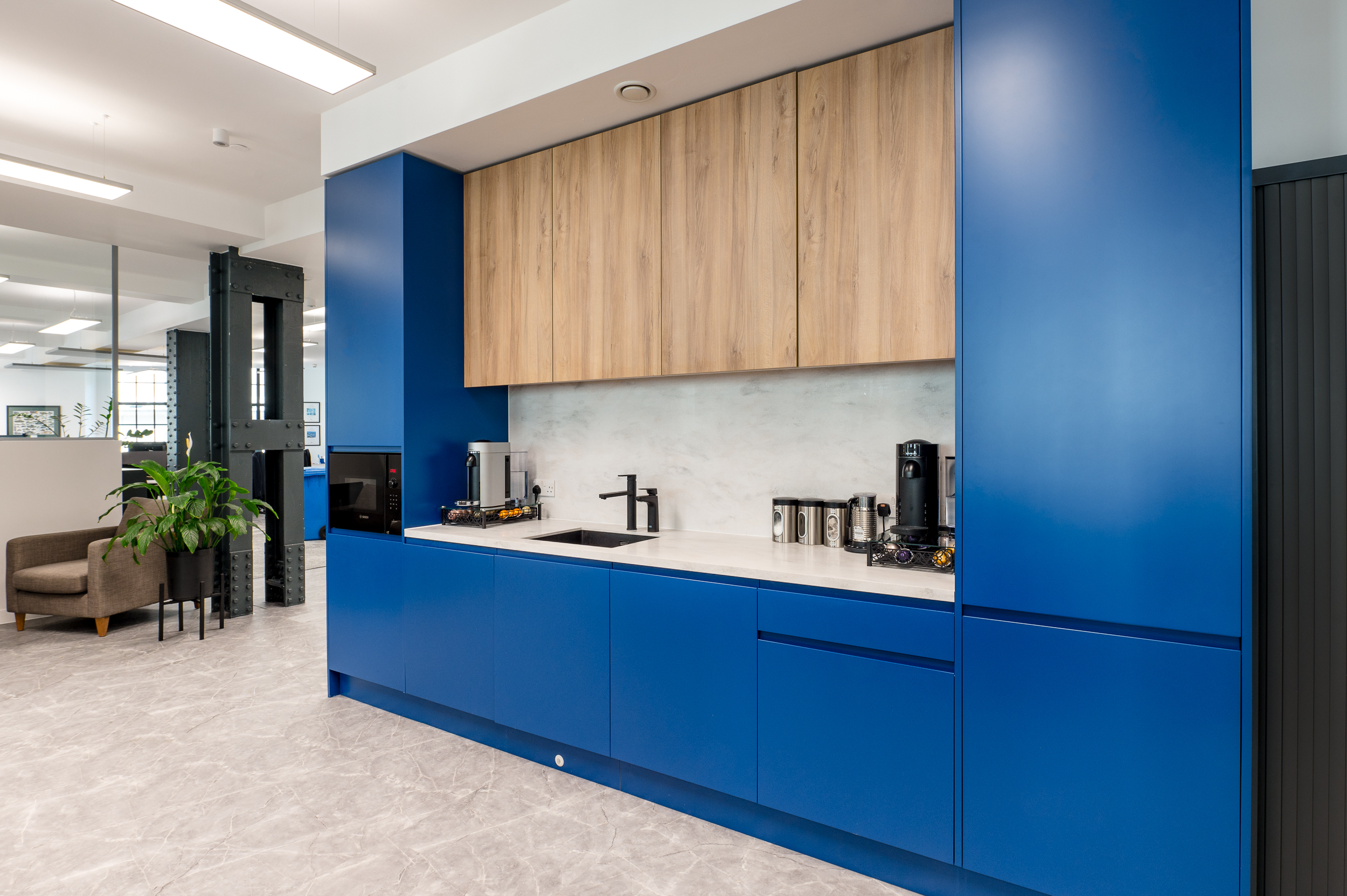 Contemporary teapoint area with bold blue cabinetry and wood accents, featuring a sleek, minimalist design.