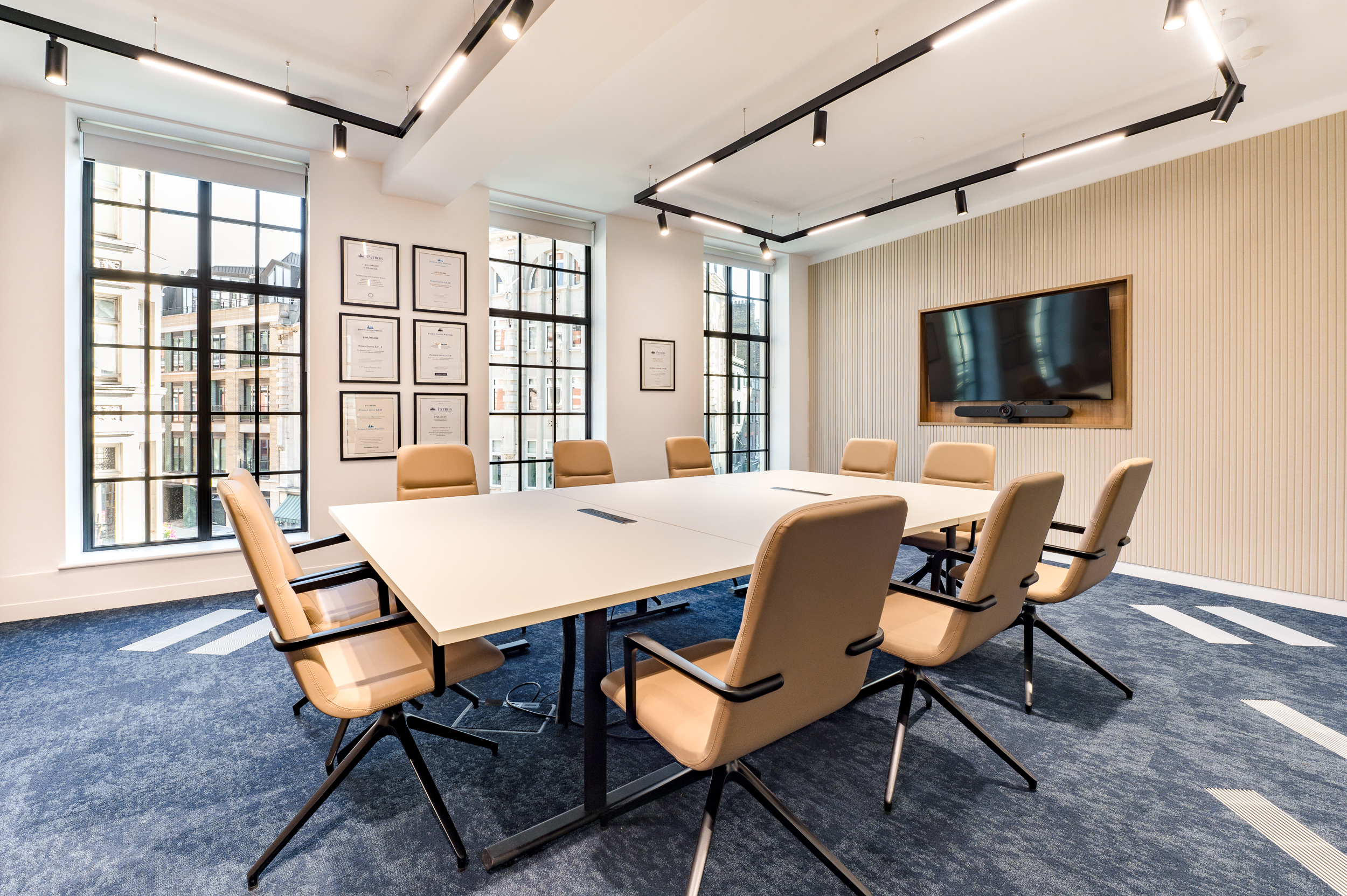 Another angle of the bright meeting room, showcasing certificates and a wall-mounted TV for presentations.