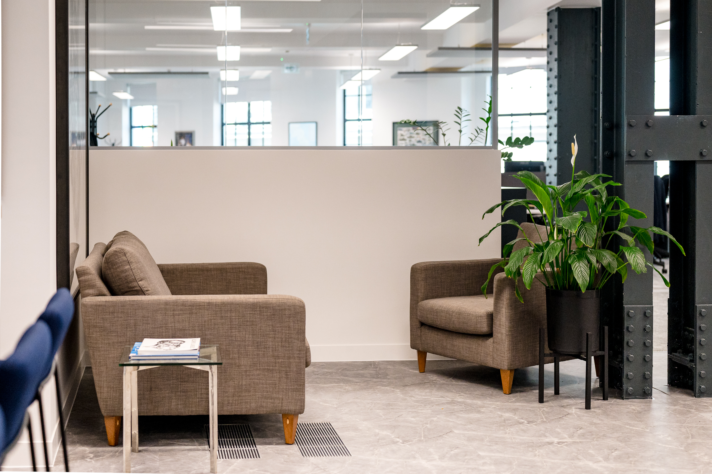 Cosy breakout seating area with armchairs and plants, set against industrial steel beams.